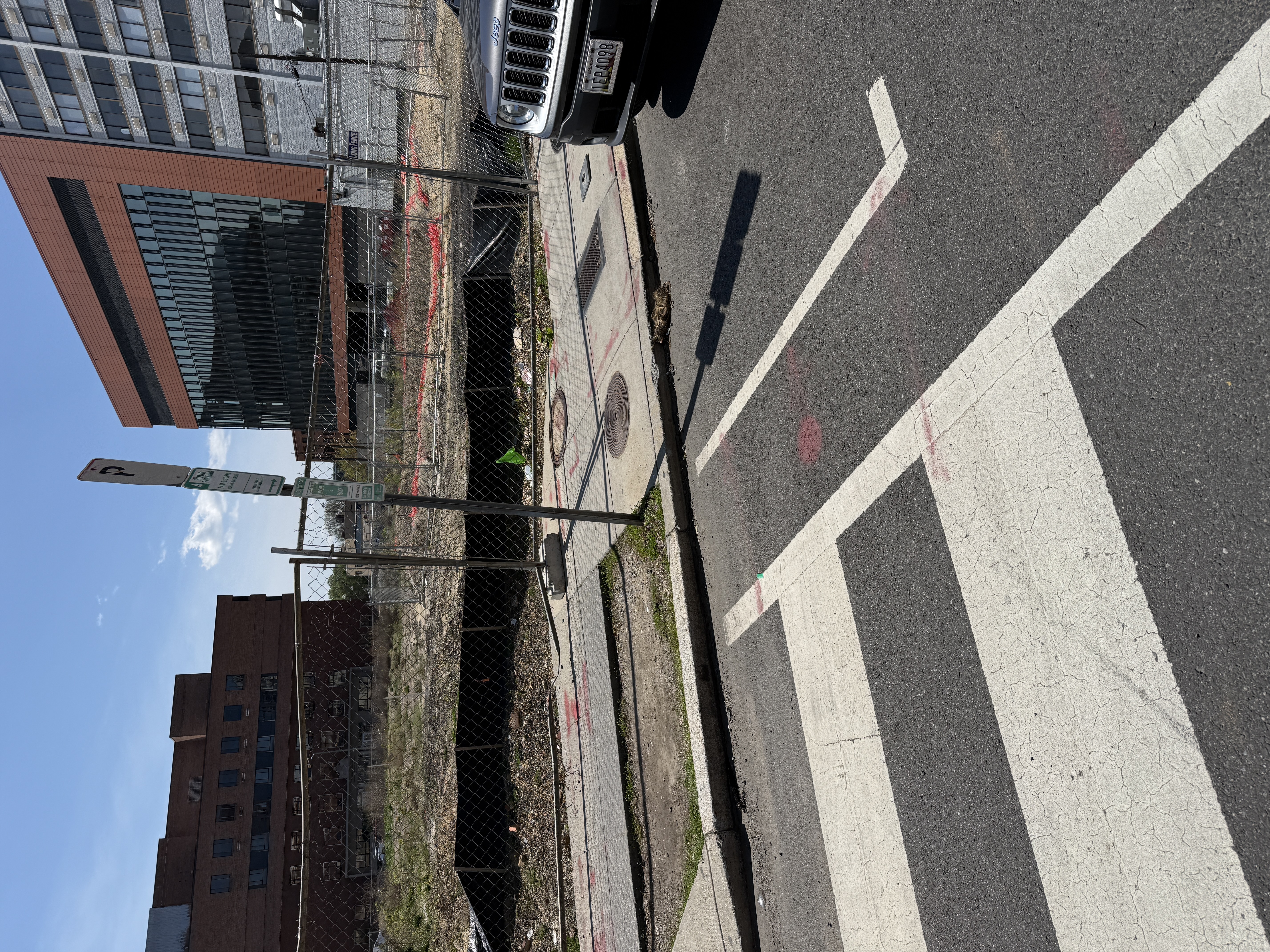 Vehicle parked right up against the crosswalk on the eastern edge of Howard University at 6th St NW. Both the parking sign on the pole and the curb-line marking on the roadway authorize parking inside the daylighting zone -- a compound DDOT failure on a fatality corridor.