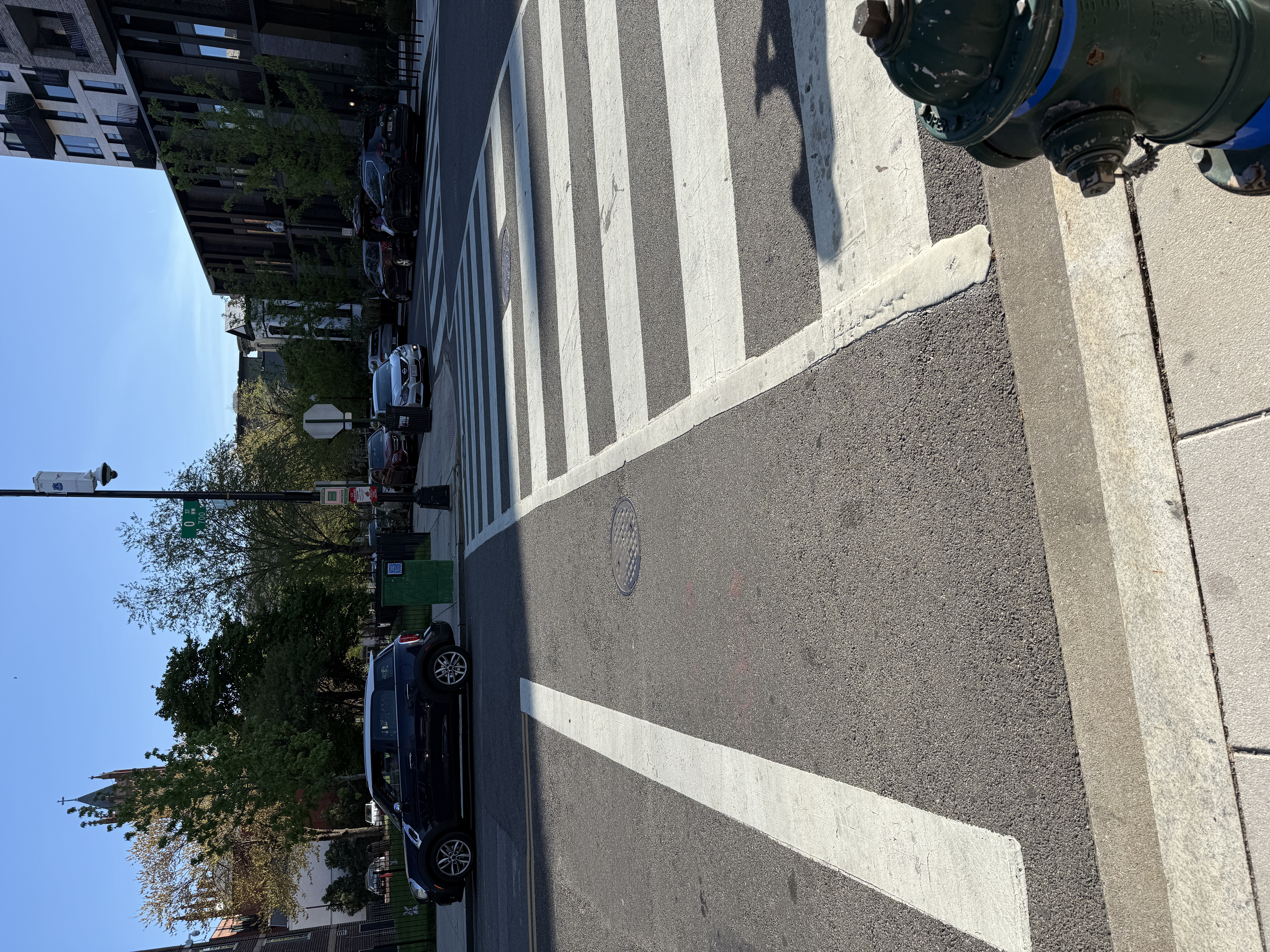A vehicle parked right up against the crosswalk at the far corner of the 700 block of O St NW -- the opposite corner from the Chevy Traverse documented a minute earlier, on the same crossing. Neither corner has a bollard, curb extension, or daylighting marking to keep vehicles back.