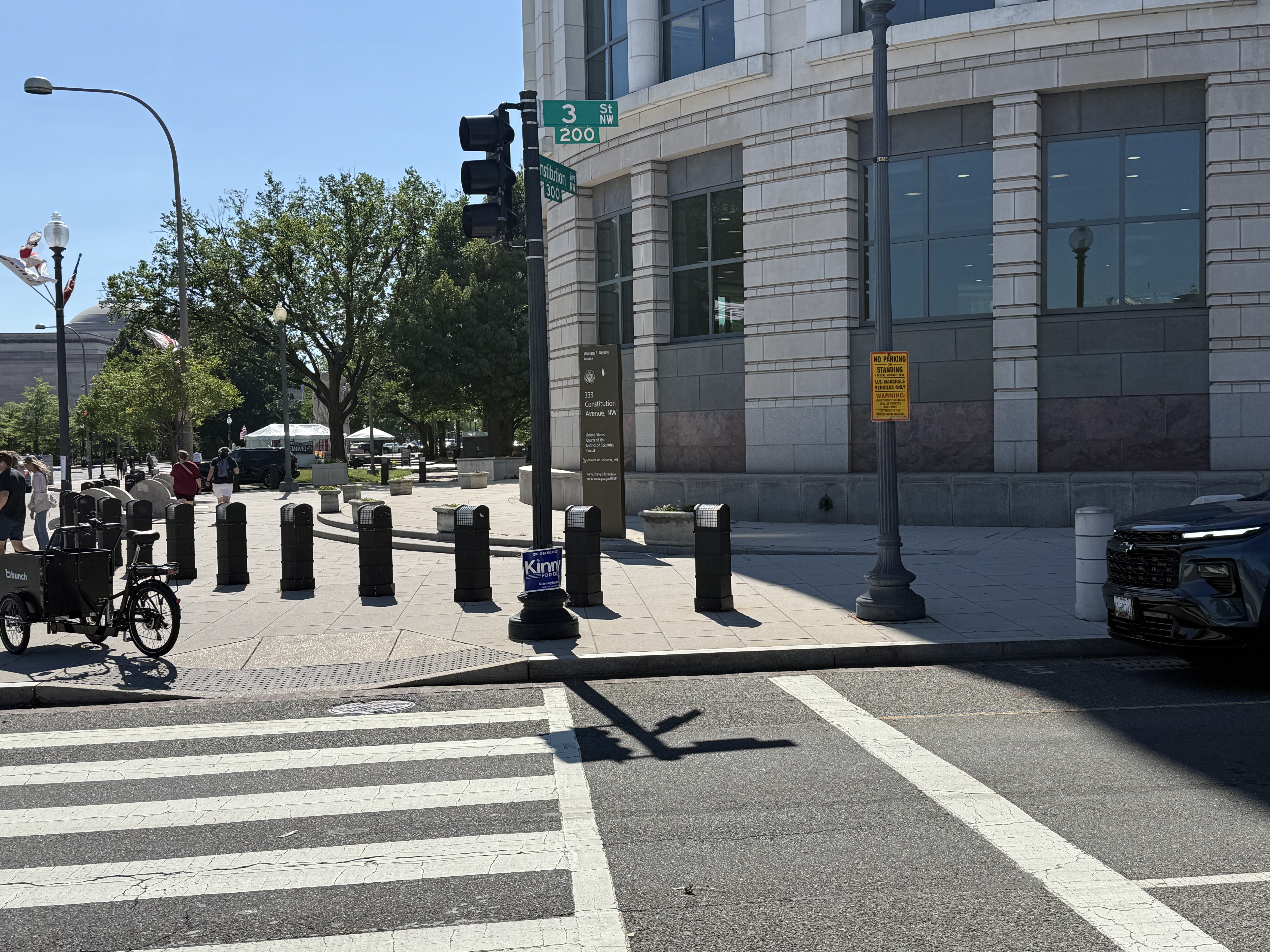 Photo 2 of 2: Federal No Parking or Standing -- U.S. Marshals Vehicles Only security-zone signs on the 200 block of 3rd Street NW at the U.S. Courthouse, designating the curb for federal vehicles right up to the marked crosswalk, with a vehicle parked flush against the crossing.