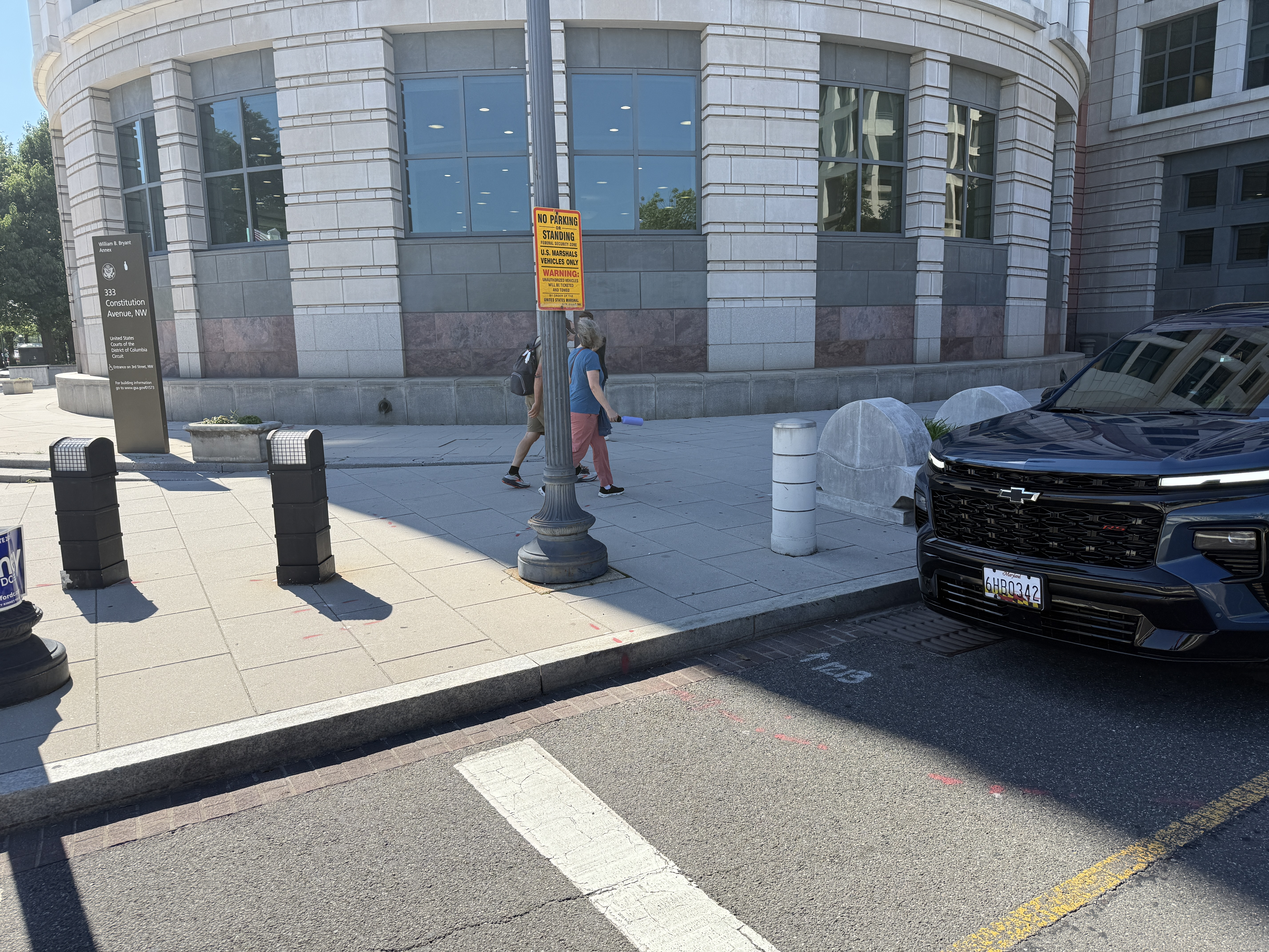 Federal No Parking or Standing -- U.S. Marshals Vehicles Only security-zone signs on the 200 block of 3rd Street NW at the U.S. Courthouse, designating the curb for federal vehicles right up to the marked crosswalk, with a vehicle parked flush against the crossing.